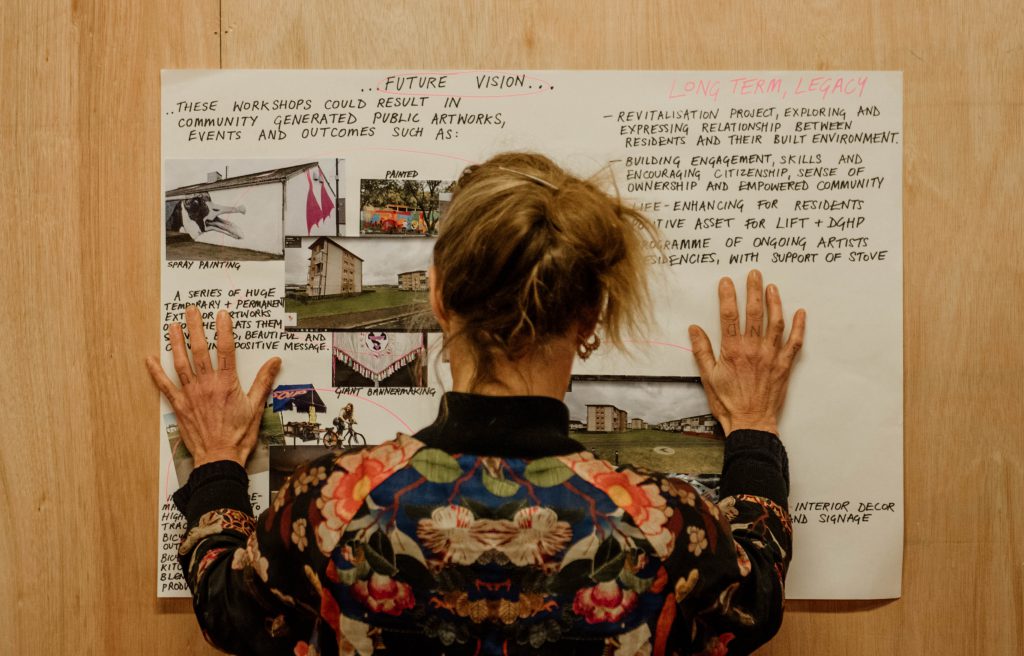 Photograph of a person in a brightly coloured floral jacket, looking at a planning poster. We cannot see their face, we are looking over their shoulder.