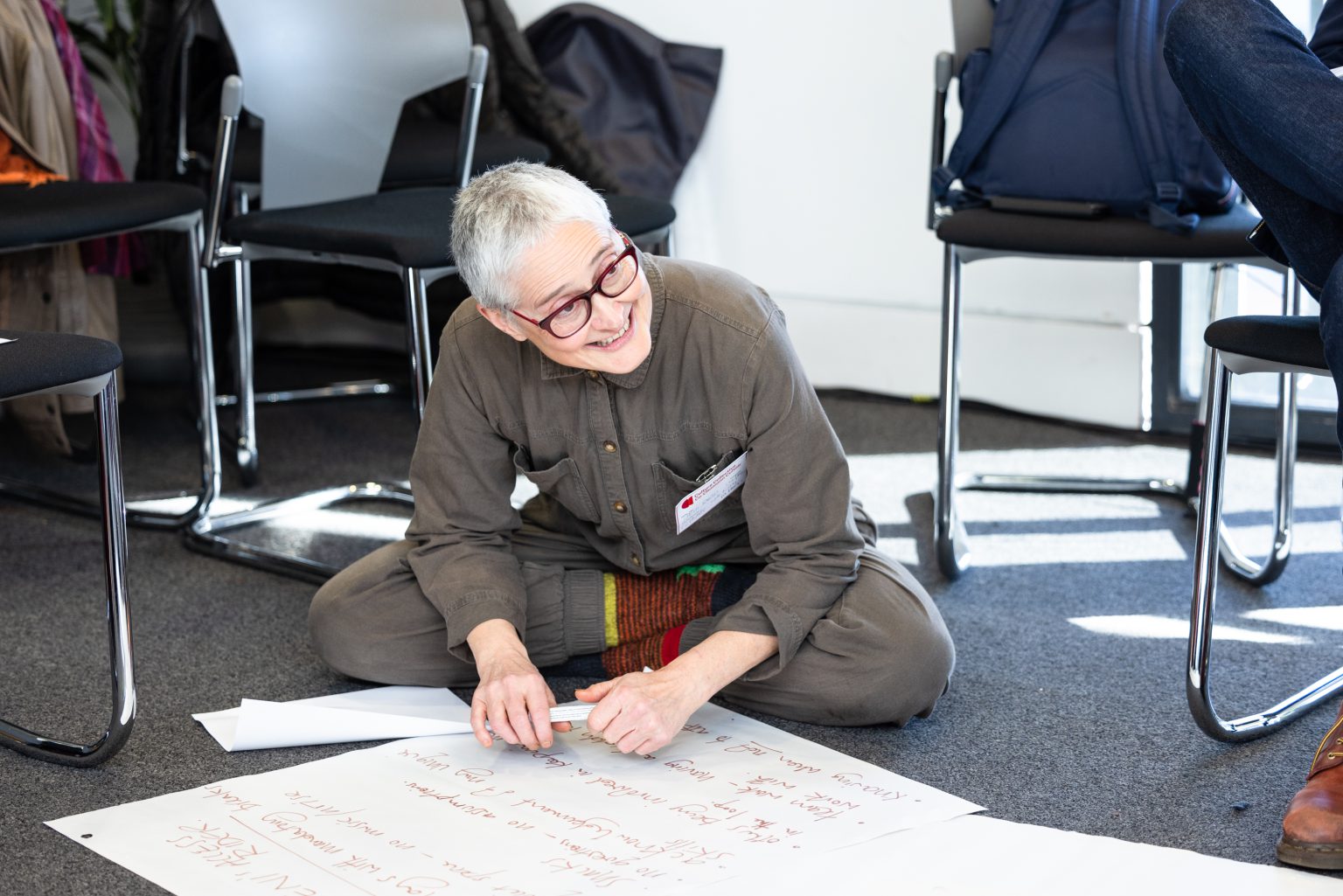 A participant smiles as they write on a large piece of paper