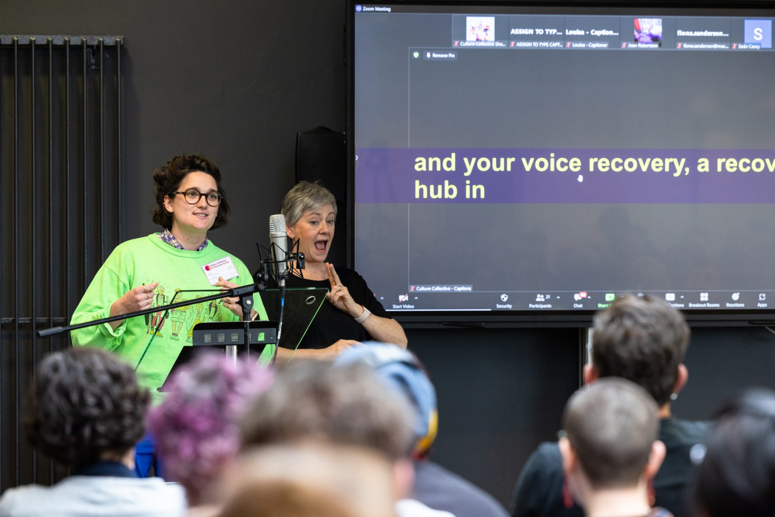 A presentation is being made by someone in a green sweater, whilst another person does a BSL interpretation.