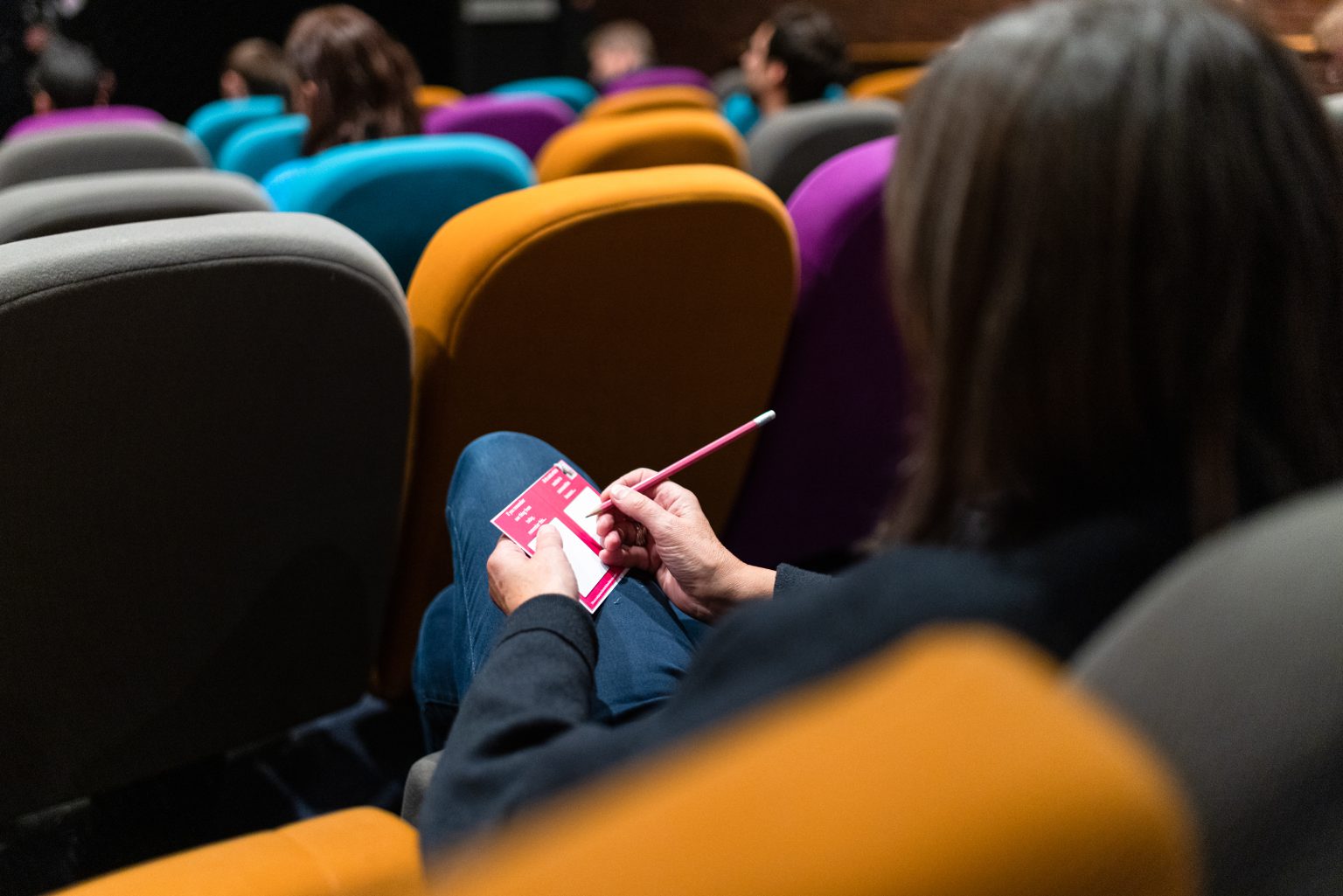 An audience member fills out the Culture Collective feedback postcard.