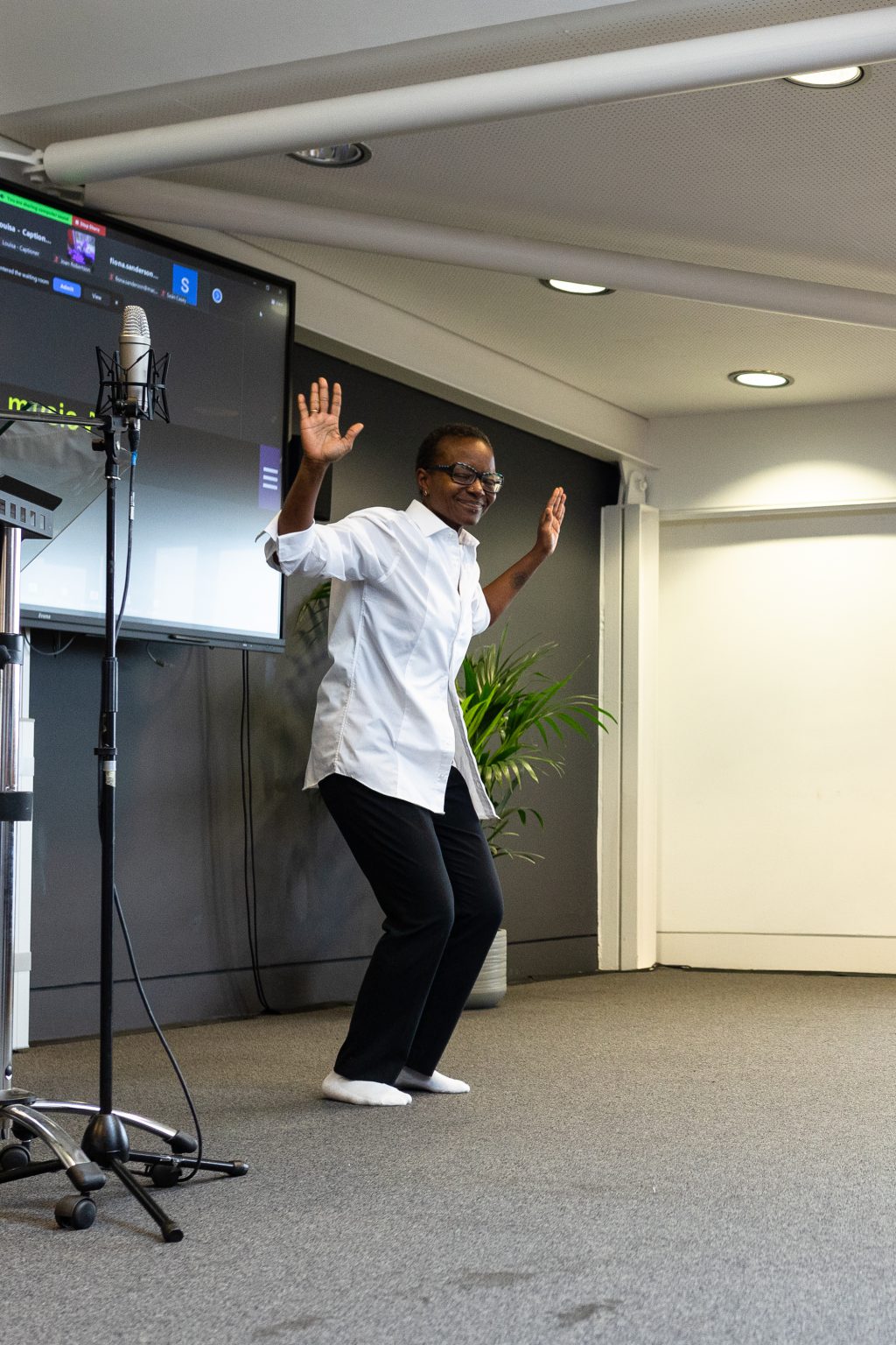 A presenter holds their arms in the air, smiling